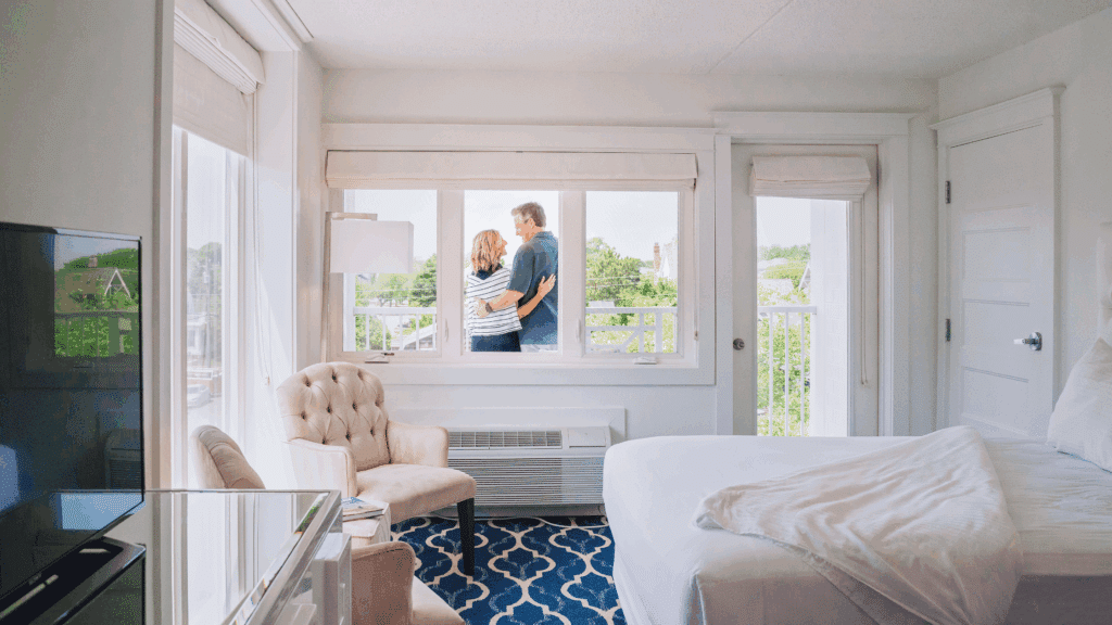 Hotel room at ICONA Cape May. Through the windows, we can see a couple embracing on the room's balcony.
