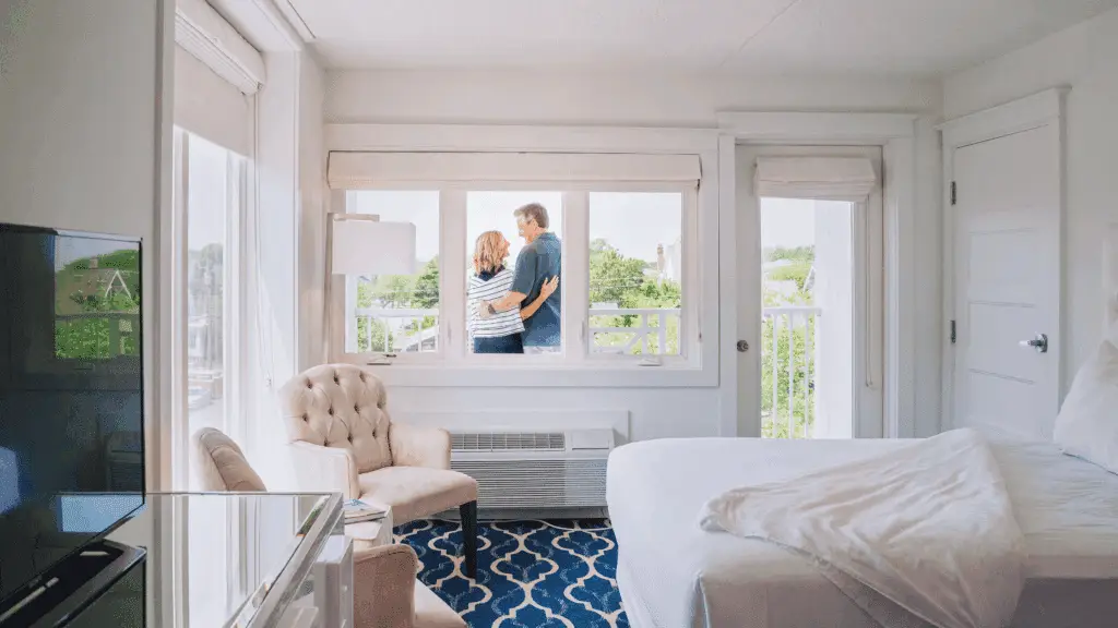 Hotel room at ICONA Cape May. Through the windows, we can see a couple embracing on the room's balcony.