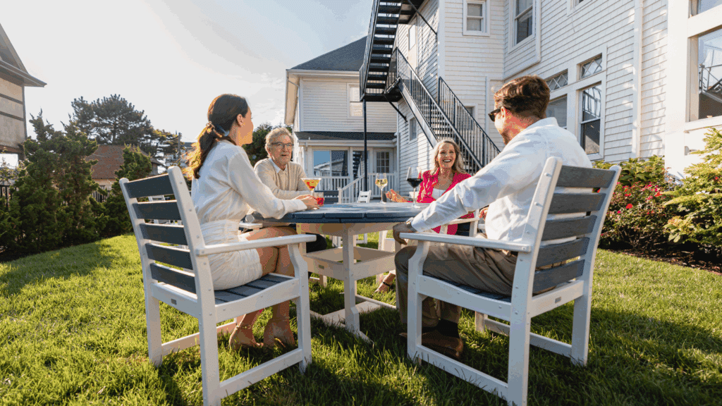 Two couples enjoying wine and conversation at a table in the Grand Victorian hotel's yard