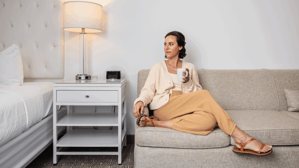Woman lounging on a couch with a cup of coffee at ICONA Diamond Beach