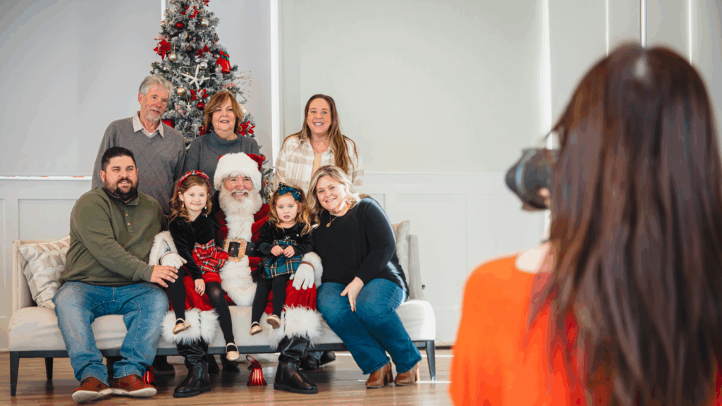 Family posing for a photo with Santa in front of a Christmas tree