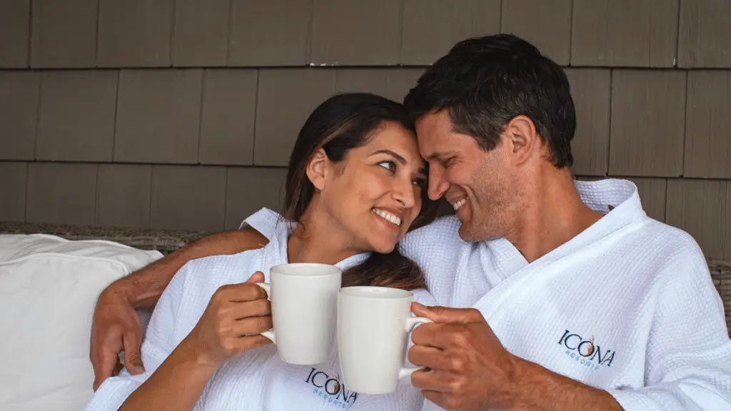 Couples cuddled up on an ICONA Resorts balcony wearing cozy robes